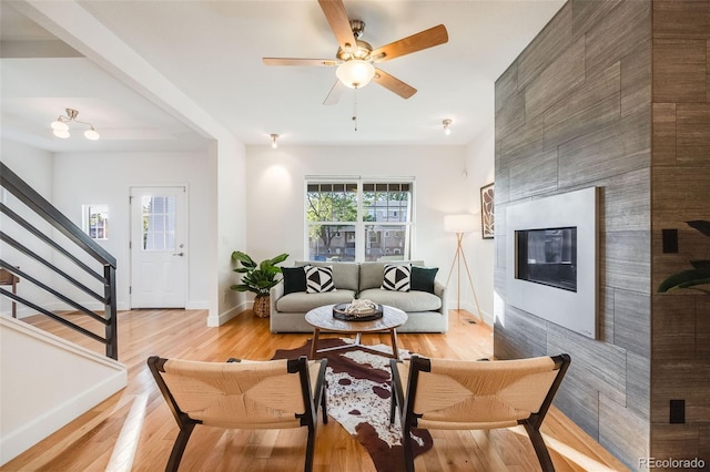 living room featuring a fireplace, ceiling fan, and light hardwood / wood-style flooring