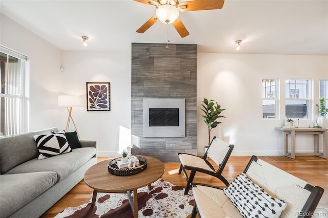 living room featuring hardwood / wood-style flooring, a wealth of natural light, a tile fireplace, and ceiling fan