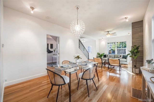 dining area with ceiling fan with notable chandelier and light hardwood / wood-style flooring