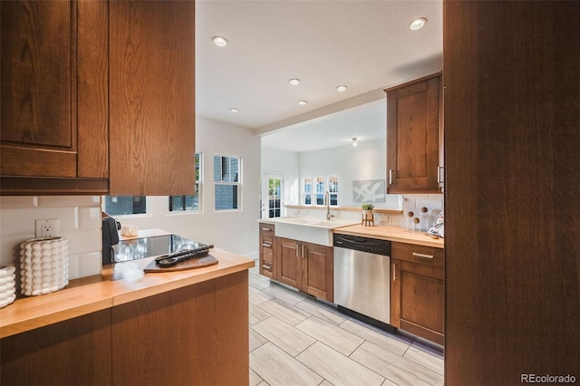 kitchen with sink, stainless steel dishwasher, butcher block countertops, and kitchen peninsula