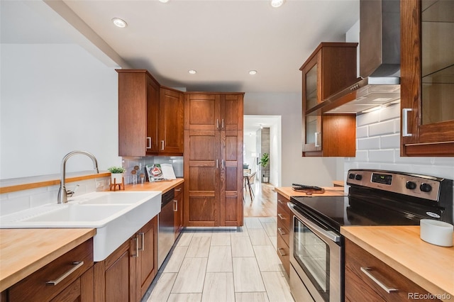 kitchen with wall chimney range hood, sink, appliances with stainless steel finishes, butcher block counters, and decorative backsplash