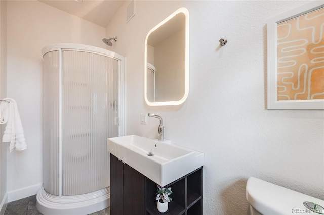 bathroom featuring vanity, toilet, and an enclosed shower