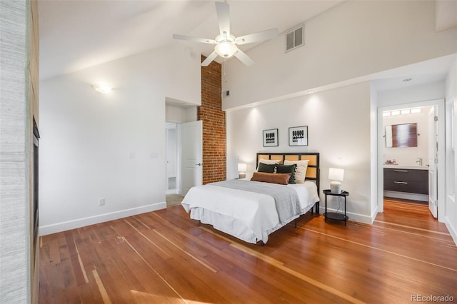 bedroom with hardwood / wood-style flooring, ceiling fan, high vaulted ceiling, and ensuite bath