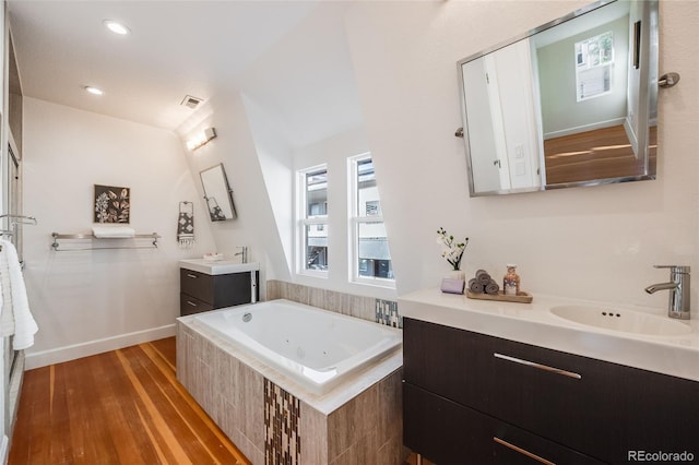 bathroom with tiled tub, vanity, and wood-type flooring