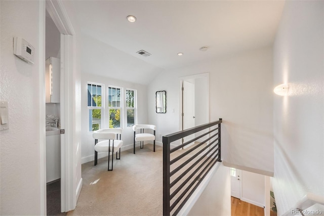 hall featuring lofted ceiling and light colored carpet