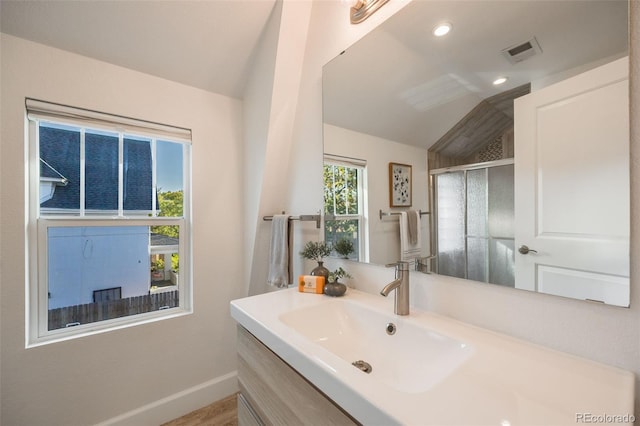 bathroom featuring lofted ceiling, vanity, and a shower with shower door