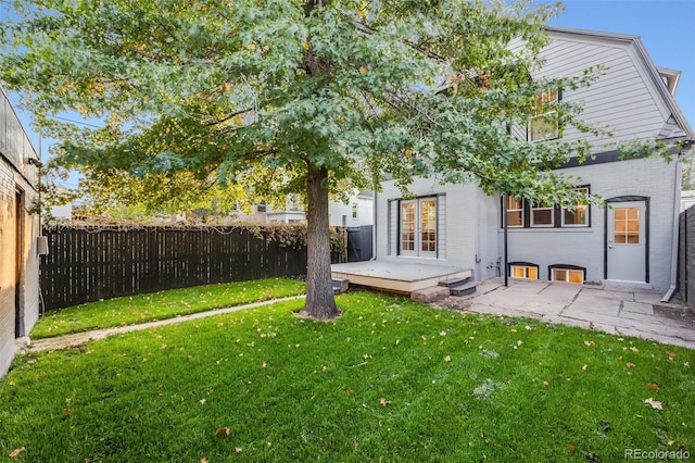 rear view of house with a wooden deck, a yard, and a patio area