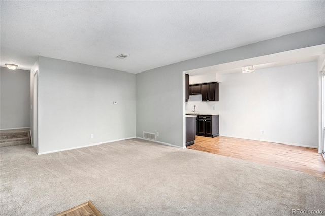 unfurnished living room featuring a textured ceiling and light hardwood / wood-style floors