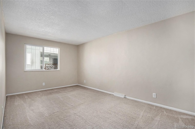 unfurnished room with carpet and a textured ceiling