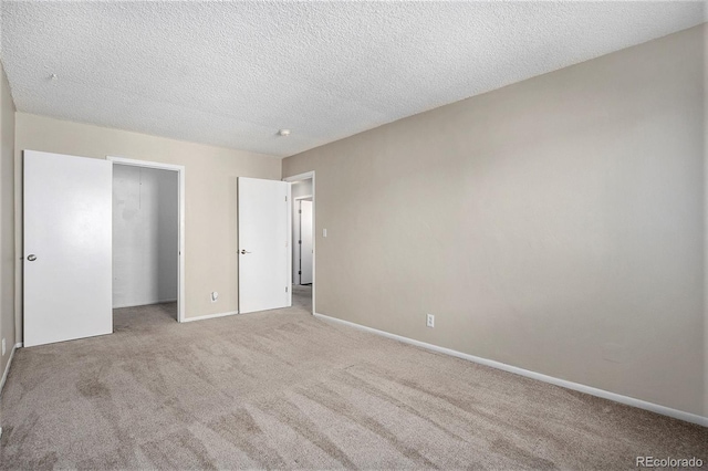 unfurnished bedroom featuring light carpet, a textured ceiling, and a closet