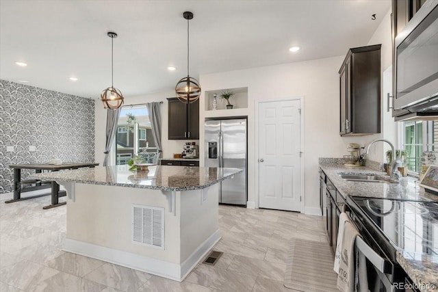 239 S Old Hammer St, Aurora, CO 80018 - kitchen featuring stainless steel appliances, plenty of natural light, stone counters, a center island, and wallpapered walls