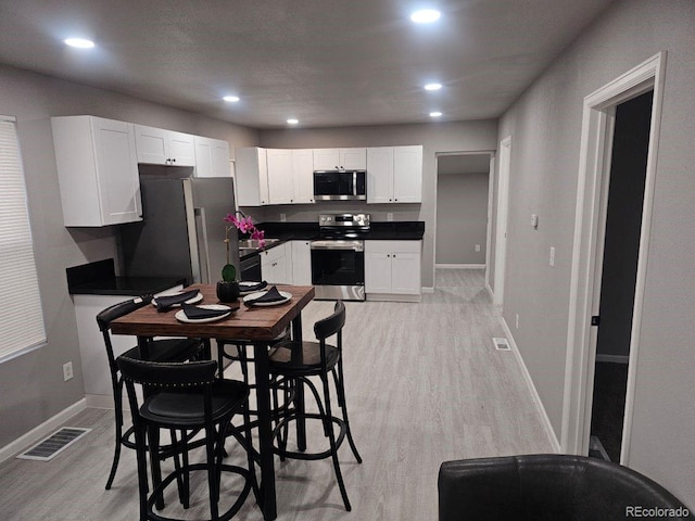 kitchen with visible vents, dark countertops, appliances with stainless steel finishes, baseboards, and light wood-style flooring