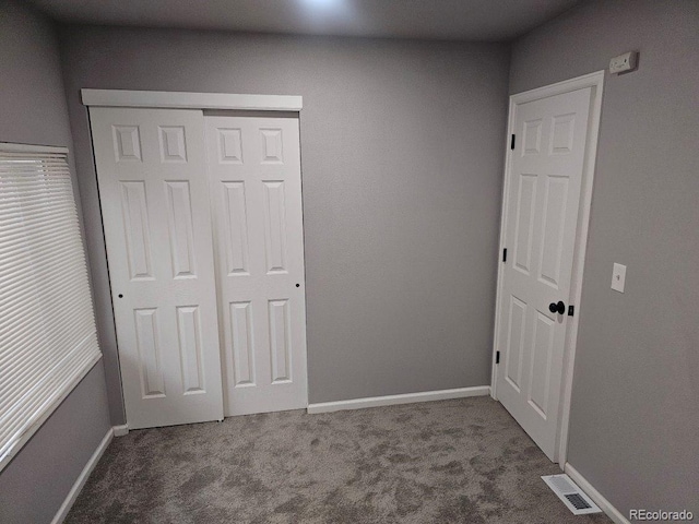 unfurnished bedroom featuring visible vents, carpet flooring, baseboards, and a closet