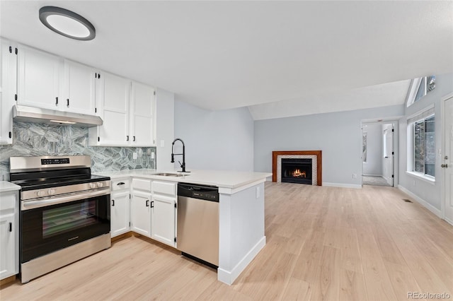 kitchen featuring lofted ceiling, kitchen peninsula, sink, stainless steel appliances, and white cabinets