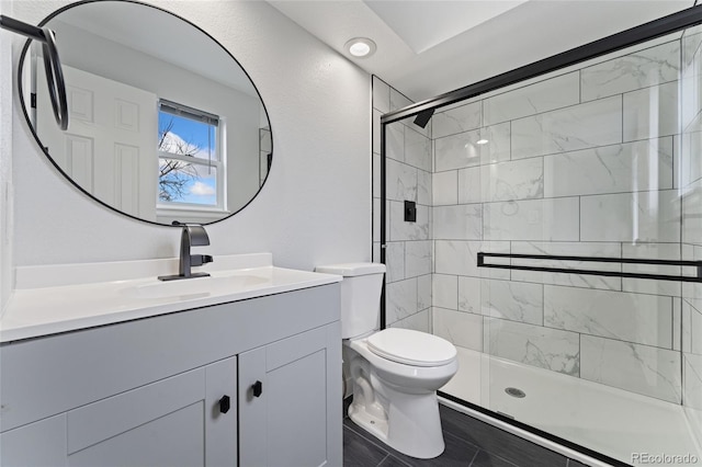 bathroom featuring a shower with shower door, vanity, and toilet