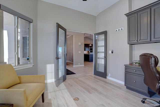 home office with lofted ceiling, light wood-type flooring, and french doors