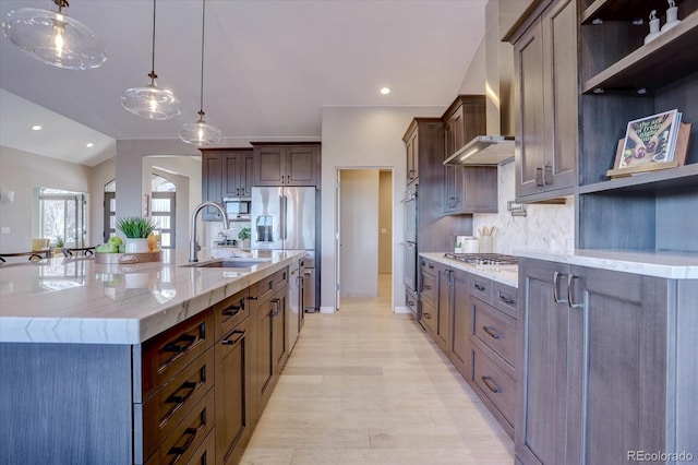 kitchen featuring sink, decorative light fixtures, wall chimney range hood, a large island, and backsplash