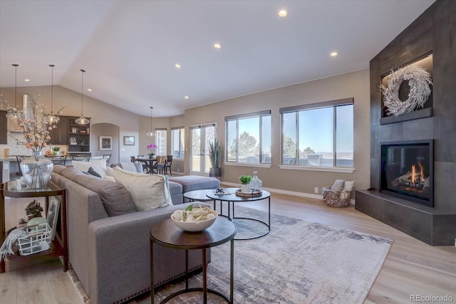 living room with vaulted ceiling, a tile fireplace, and light hardwood / wood-style flooring