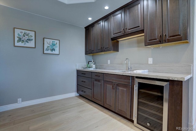 kitchen featuring wine cooler, sink, dark brown cabinets, and light hardwood / wood-style floors