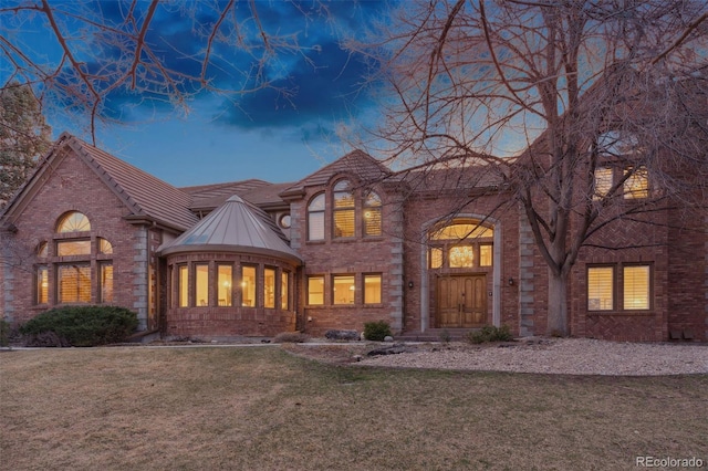 5 Tamarade Dr, Littleton, CO 80127 - back of house at dusk with a standing seam roof, a yard, brick siding, and metal roof