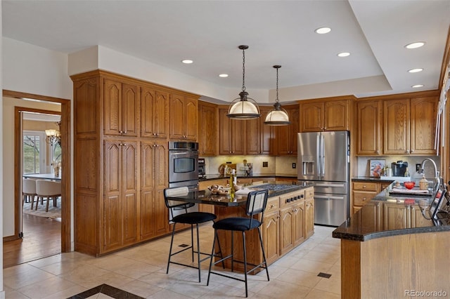 5 Tamarade Dr, Littleton, CO 80127 - kitchen featuring brown cabinetry, a kitchen island, a sink, stainless steel appliances, and a breakfast bar area