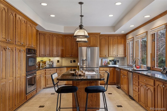 5 Tamarade Dr, Littleton, CO 80127 - kitchen featuring a tray ceiling, a center island, appliances with stainless steel finishes, and brown cabinetry