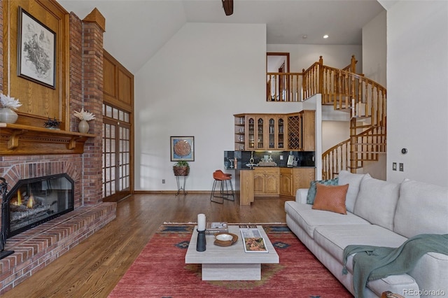 5 Tamarade Dr, Littleton, CO 80127 - living room featuring baseboards, a fireplace, stairway, high vaulted ceiling, and wood finished floors