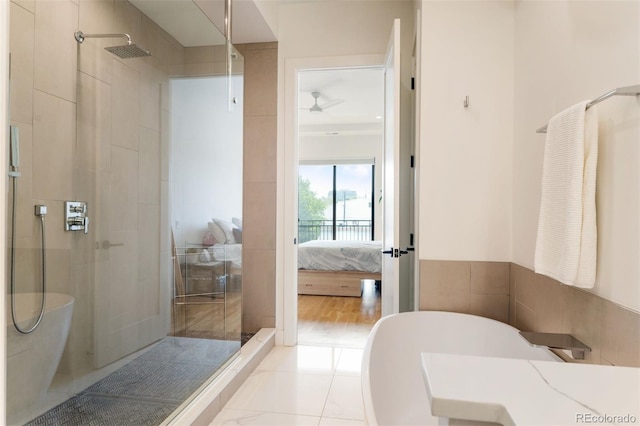 ensuite bathroom featuring tile walls, a freestanding bath, a shower stall, and ensuite bathroom