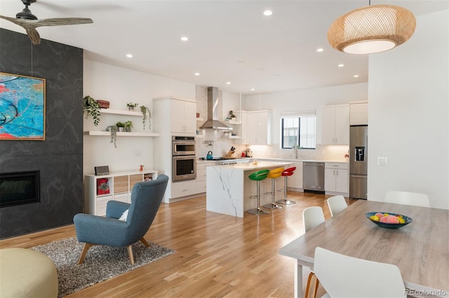 interior space featuring a ceiling fan, a fireplace, light wood-style flooring, and recessed lighting