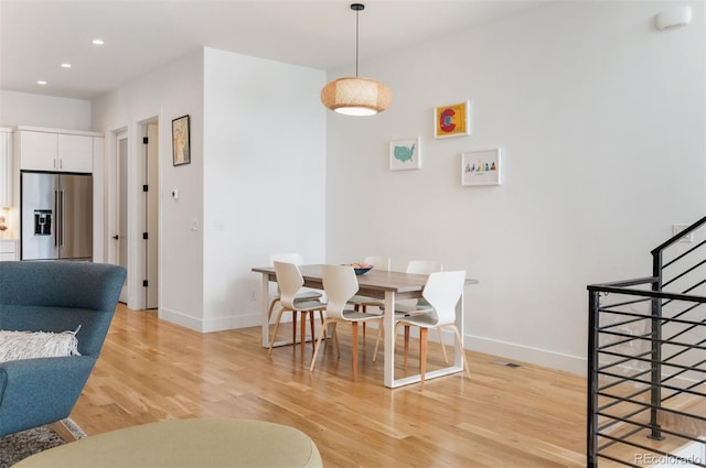 dining area featuring light wood-style floors, recessed lighting, baseboards, and stairs