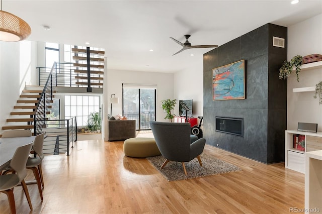 living area featuring light wood-style floors, stairs, visible vents, and a tiled fireplace