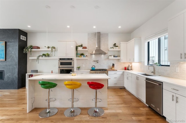 kitchen with open shelves, wall chimney range hood, a sink, and stainless steel appliances