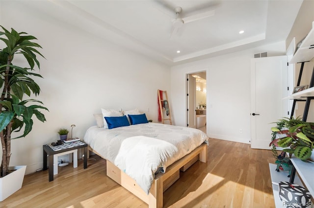 bedroom featuring recessed lighting, a raised ceiling, visible vents, light wood-style flooring, and connected bathroom