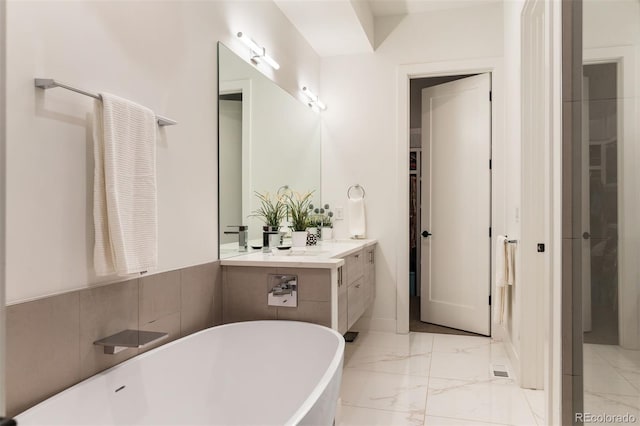 full bathroom featuring marble finish floor, a freestanding tub, and vanity