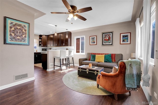 living room featuring ceiling fan, a healthy amount of sunlight, and dark hardwood / wood-style flooring