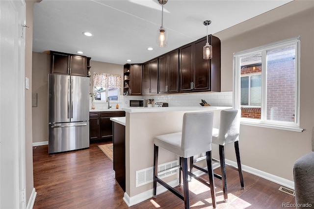 kitchen featuring pendant lighting, stainless steel refrigerator, a breakfast bar area, and dark hardwood / wood-style floors