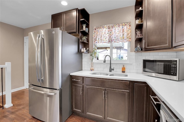 kitchen with appliances with stainless steel finishes, decorative backsplash, sink, and dark hardwood / wood-style flooring