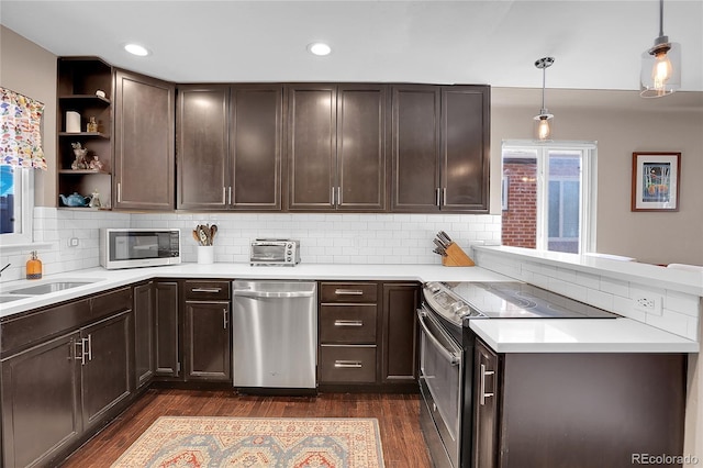 kitchen with pendant lighting, dark brown cabinets, backsplash, appliances with stainless steel finishes, and dark hardwood / wood-style flooring