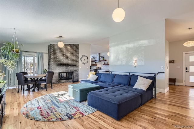 living room featuring vaulted ceiling, a fireplace, and hardwood / wood-style flooring