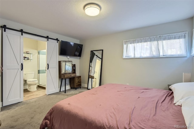 carpeted bedroom featuring a barn door and ensuite bath