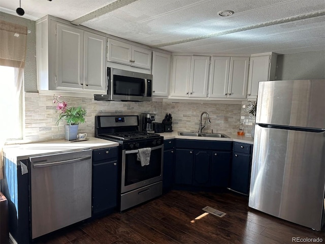 kitchen featuring blue cabinetry, white cabinetry, appliances with stainless steel finishes, and sink