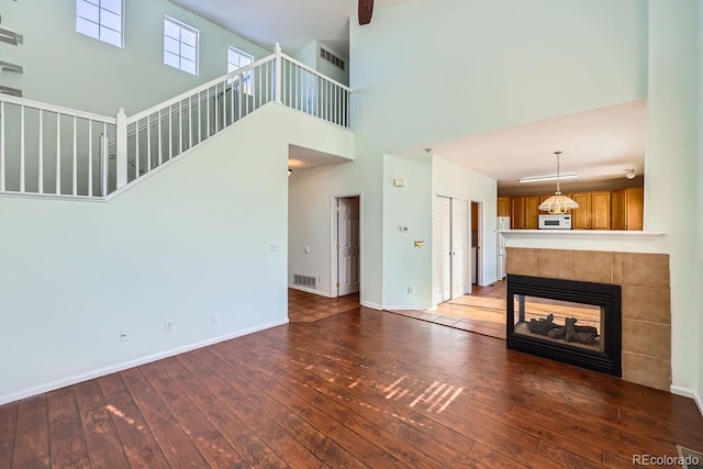 unfurnished living room with a multi sided fireplace, dark hardwood / wood-style flooring, and a high ceiling