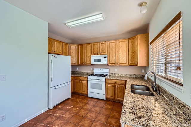 kitchen with white appliances, stone countertops, dark tile patterned floors, and sink