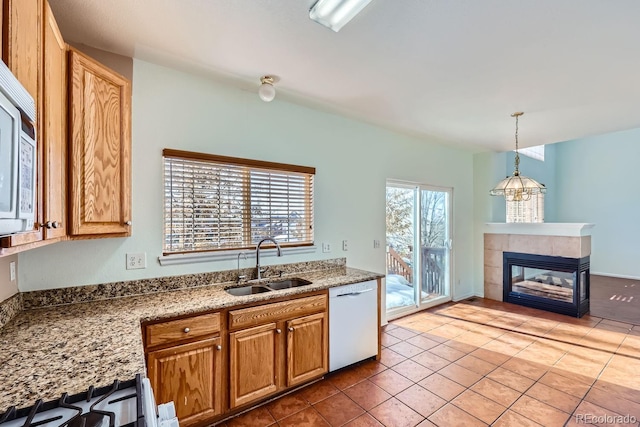 kitchen featuring white appliances, sink, pendant lighting, tile patterned flooring, and a tiled fireplace