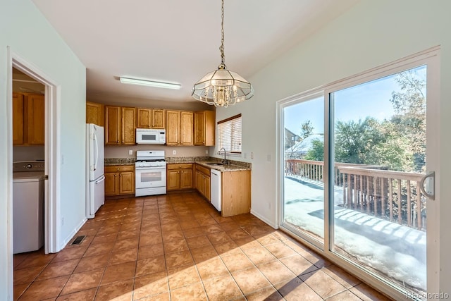 kitchen featuring sink, hanging light fixtures, an inviting chandelier, light stone counters, and white appliances