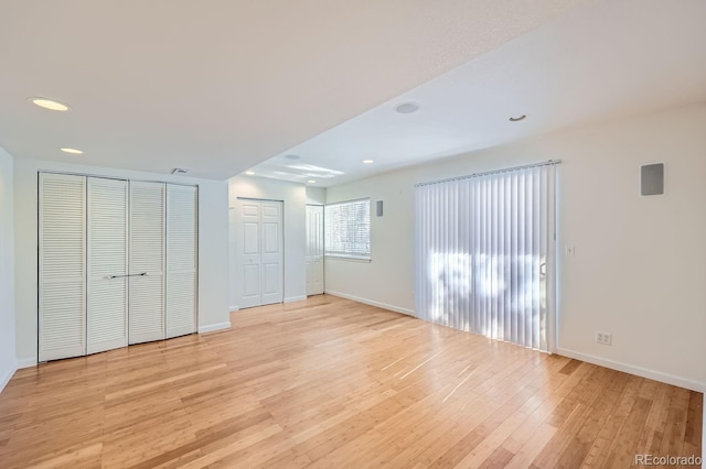 unfurnished bedroom featuring light wood-type flooring and multiple closets