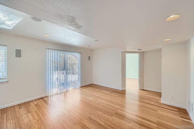 unfurnished room featuring light hardwood / wood-style floors and a textured ceiling