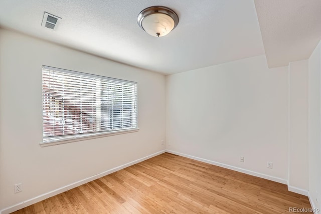 unfurnished room with light hardwood / wood-style floors and a textured ceiling