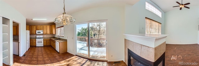 kitchen featuring sink, vaulted ceiling, decorative light fixtures, white appliances, and a tiled fireplace