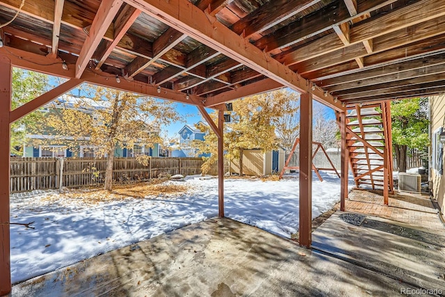 snow covered patio featuring a storage unit